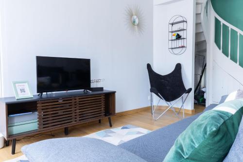 a living room with a television and a chair at La Récrée des Pandas Maison de ville 6pers, Châteauvieux, Zoo de Beauval, Châteaux de la Loire in Châteauvieux