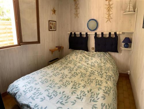 a bedroom with a bed with a blue and white comforter at « La Palmeraie » Villa résidentielle avec piscine in La Palmyre
