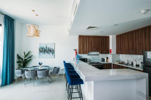 a kitchen with a island with blue stools at Relaxing villa with access to pool and beach in Ras al Khaimah