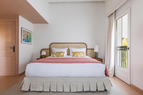 een witte slaapkamer met een groot bed en een raam bij Hôtel La Tartane Saint-Tropez in Saint-Tropez