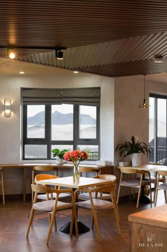 a dining room with a table and chairs and windows at De La Sol Villa Dalat in Da Lat