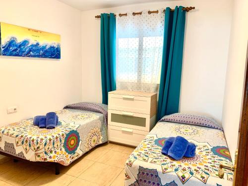 コラレホにあるFuertelena Corralejo Soul Apartmentの青いカーテン付きのベッドルームのベッド2台