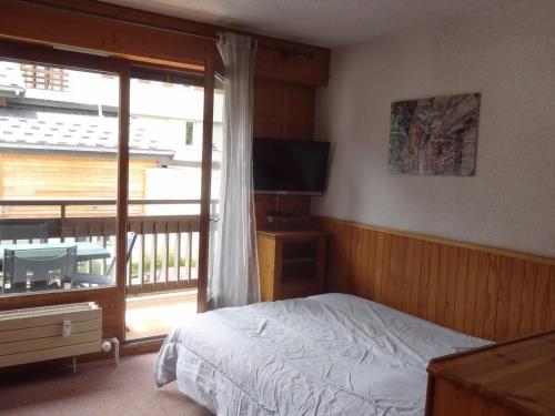 a bedroom with a bed and a balcony with a television at Studio Valloire, 1 pièce, 3 personnes - FR-1-263-491 in Valloire