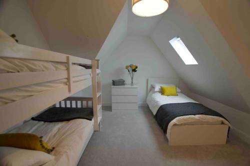 a attic bedroom with two bunk beds and a window at New stylish 4 bed house moments from Clacton beach in Clacton-on-Sea