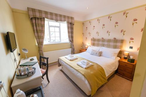 a bedroom with a bed and a desk and a television at Fox And Hounds Llancarfan in Barry
