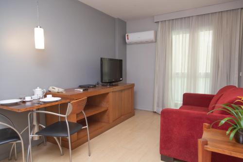 a living room with a tv and a red couch at Lobie Queen Ipanema in Rio de Janeiro