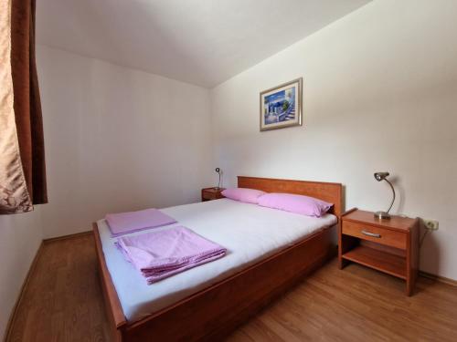 - une chambre avec un lit avec des draps roses et une table de chevet dans l'établissement Apartments Lacic 3, à Crikvenica