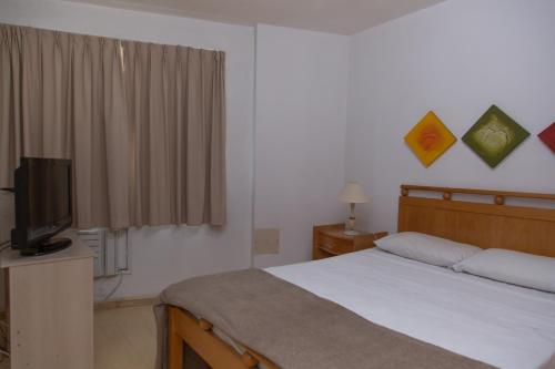 a bedroom with a bed and a flat screen tv at Lobie Queen Ipanema in Rio de Janeiro