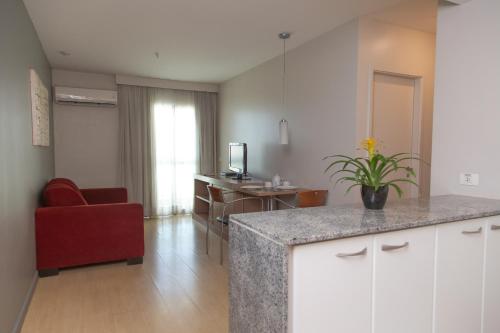a kitchen and living room with a counter and a red chair at Lobie Queen Ipanema in Rio de Janeiro