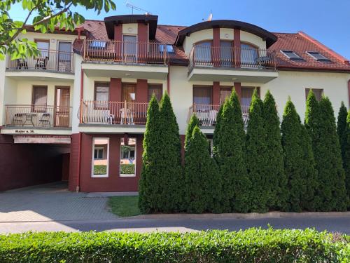 an apartment building with trees in front of it at Major Panzió és Étterem in Hajdúszoboszló