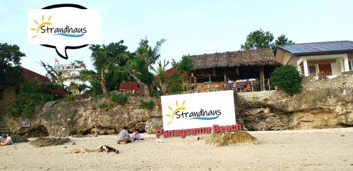 a group of people sitting on a beach with a sign at Strandhaus Condotel in Moalboal