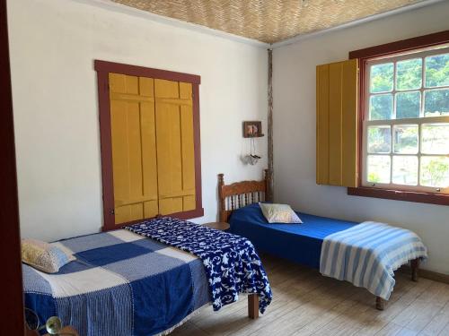 1 dormitorio con 2 camas y 2 ventanas en Sítio Santa Rita, en Prados