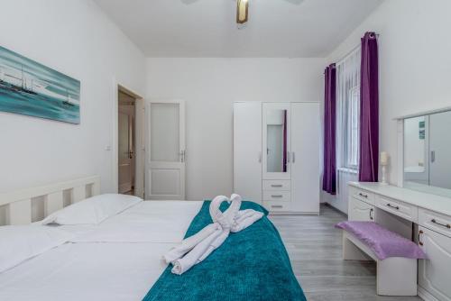 a white bedroom with a large bed with a towel on it at Buenas Noches in Split