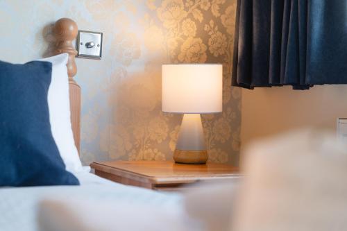 a lamp on a night stand next to a bed at Fox And Hounds Llancarfan in Barry