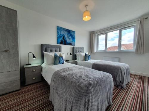 1 Schlafzimmer mit 2 Betten und einem Fenster in der Unterkunft Cheerful 4 - Tranquil Oasis Modern and Spacious Retreat 4-Bedroom with Private Parking and Serene Gardens in Luton
