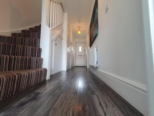 an empty hallway with a couch and stairs in a house at Cheerful 4 - Tranquil Oasis Modern and Spacious Retreat 4-Bedroom with Private Parking and Serene Gardens in Luton
