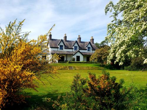 an old house on a green field with trees at Bryansford Cottage Stables in Bryansford