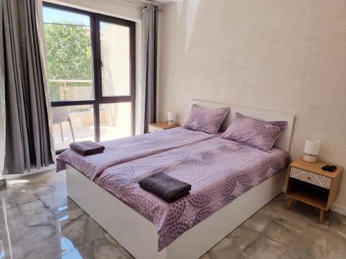 a bedroom with a bed with purple sheets and a window at СТУДИО АВА in Sliven