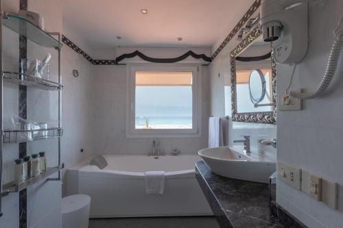 a white bathroom with a tub and a sink at Hotel 1908 in Forte dei Marmi