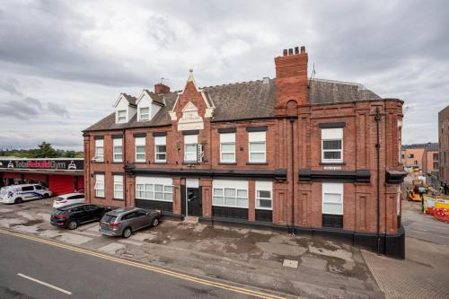 a large brick building with cars parked in front of it at Dusties Hotel in Rotherham
