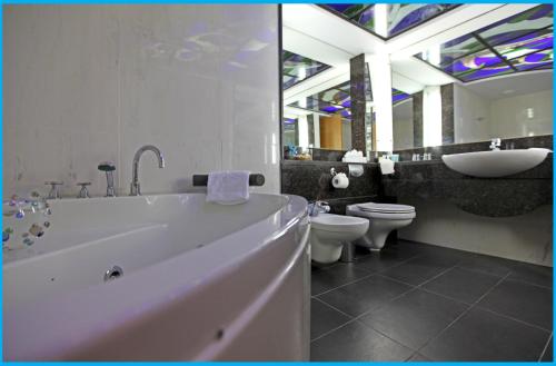 a bathroom with a tub and a sink and a toilet at Poseidonia Beach Hotel in Limassol