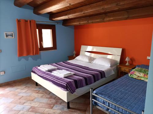 a bedroom with two beds and an orange wall at Casolare La Torre in Scopello