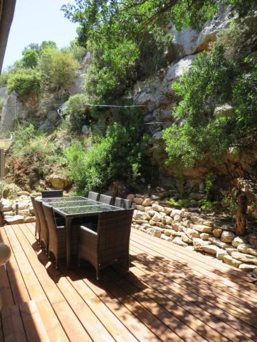 une table et des chaises sur une terrasse à côté d'un mur de roche dans l'établissement Villa Ripaud, private river swimming, hot tub, à Villesèque-des-Corbières