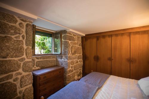una camera con letto e parete in pietra di Casa Pereira a Balança