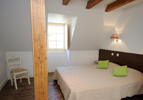Un dormitorio con una cama con almohadas verdes y una ventana. en Le Clos des Rives, en Saint-Vincent-de-Cosse