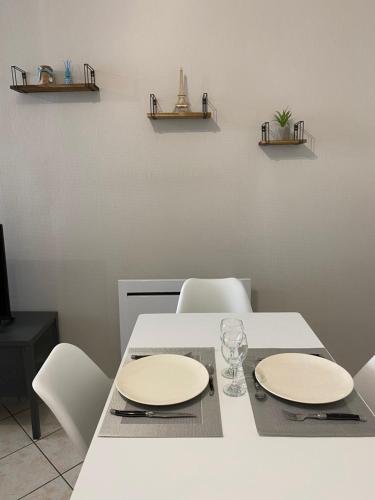 - une table blanche avec deux assiettes et des verres dans l'établissement Esprit Cosy Centre Ville, à Roanne