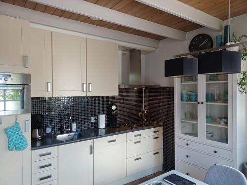 a white kitchen with white cabinets and black tiles at Karakteristiek huis in centrum Winsum met nieuwe badkamer in Winsum