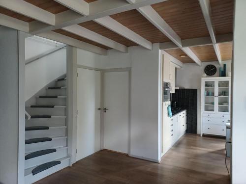a staircase in a kitchen with white walls and wooden ceilings at Karakteristiek huis in centrum Winsum met nieuwe badkamer in Winsum