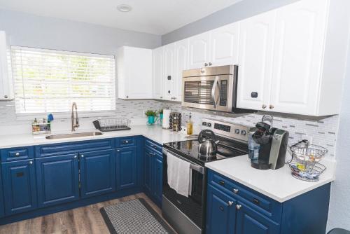 a kitchen with blue cabinets and a stove top oven at Golfers Paradise 4-hole PUTT-PUTT, Mega Chess with huge backyard, hammock in Jupiter