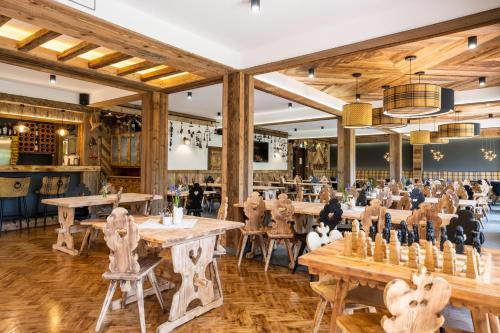 a restaurant with wooden tables and chairs and a game room at Willa Cztery Pory Roku in Kościelisko