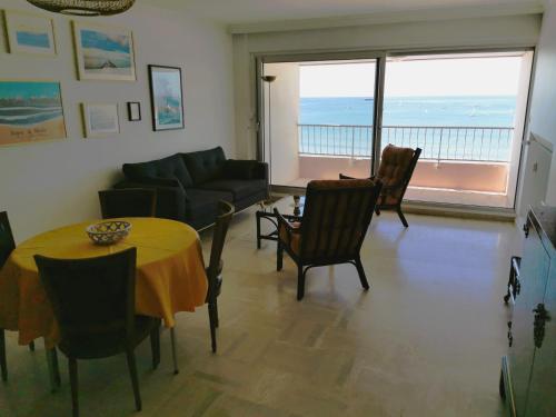 un salon avec une table, des chaises et un canapé dans l'établissement Le Foch - Appartement face mer avec garage, à Les Sables-dʼOlonne