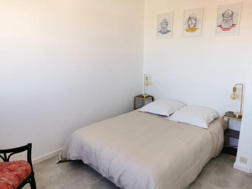 een slaapkamer met een wit bed en een rode stoel bij Le Foch - Appartement face mer avec garage in Les Sables-dʼOlonne