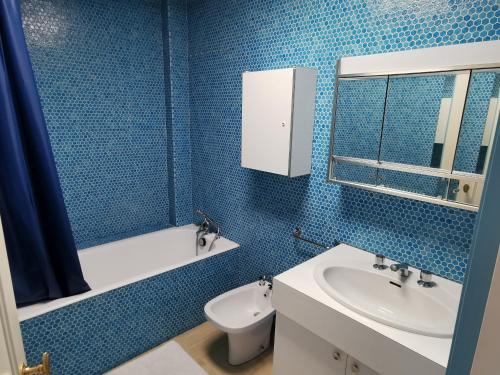 ein blau gefliestes Bad mit einem Waschbecken und einem WC in der Unterkunft Le Foch - Appartement face mer avec garage in Les Sables-dʼOlonne