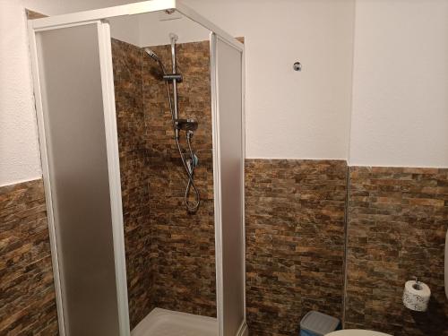 a shower in a bathroom with a brick wall at Casolare La Torre in Scopello