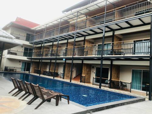 a large building with a swimming pool and two benches at Celosia Chiang Mai Hotel in Chiang Mai