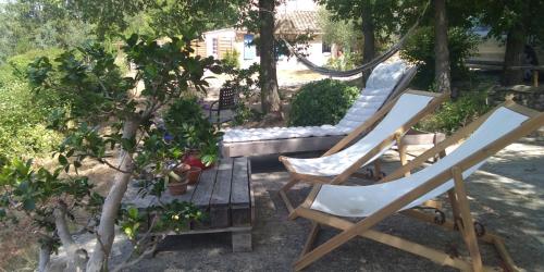 two chairs and a bench in a yard at Bienvenue à la Source dans une Maison de Charme in Apt