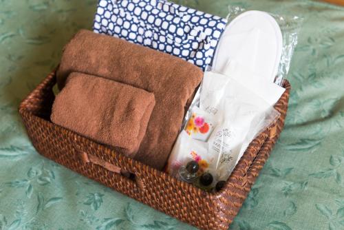 a basket with towels and other items on a bed at Pension Yufuin in Yufuin