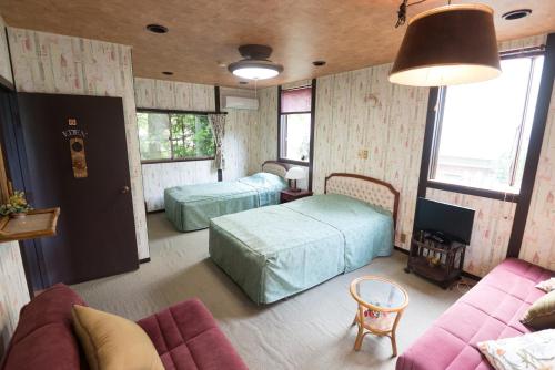 salon z 2 łóżkami i kanapą w obiekcie Pension Yufuin w mieście Yufu