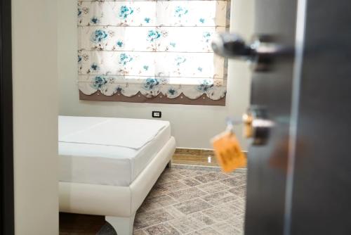 1 dormitorio con cama blanca y ventana en Hotel Magic en Gjirokastër