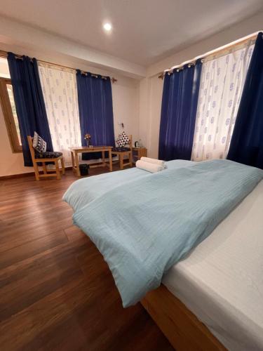 a bedroom with blue curtains and a large bed at The Doors Inn in Manāli