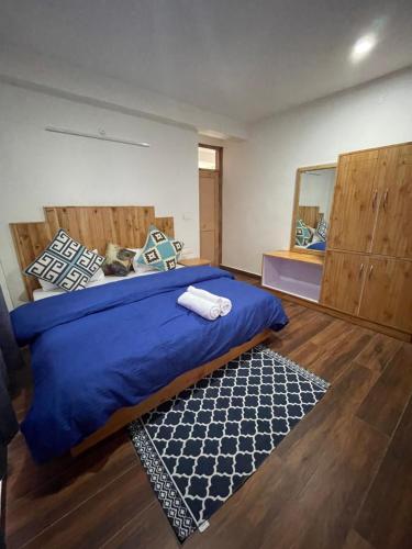 a bedroom with a bed with a blue comforter and a mirror at The Doors Inn in Manāli