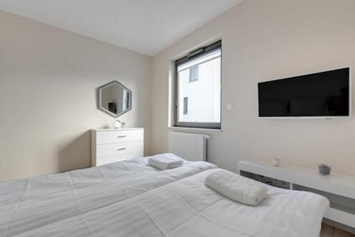 um quarto branco com uma cama grande e uma televisão de ecrã plano em Apartament OldNova em Gdansk