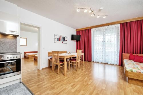 エック・アム・ファーカー・ゼーにあるApartments Weberhofのテーブルと椅子のあるキッチンとリビングルーム