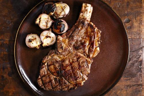 a plate with a piece of steak and some onions at Mizpe Hayamim by Isrotel Exclusive in Rosh Pinna