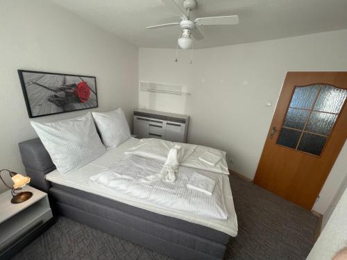 1 dormitorio con 1 cama con sábanas blancas y ventilador en Apartament Regina, en Ustka