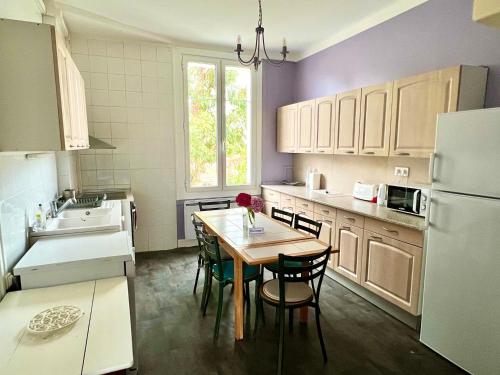 une cuisine avec une table avec des chaises et un réfrigérateur dans l'établissement Grand Appartement dans une Maison, à Bayonne